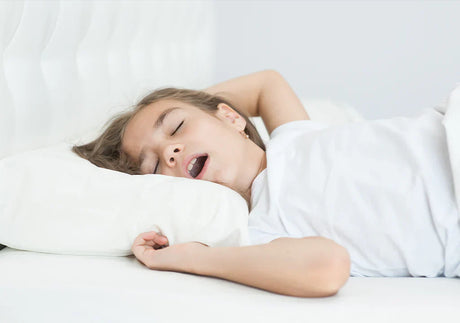 Child sleeping peacefully in bed with white pillow and bedding