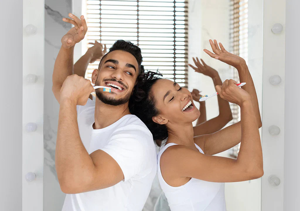 Happy couple brushing teeth together in bathroom, smiling and playful in front of mirror