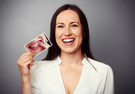 Smiling woman holding photo of stained teeth from smoking, showcasing teeth whitening results